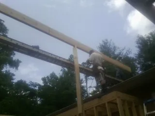 Carpenter setting a ridge beam over a new addition frame — Ice Dam Removal by Roofing Brothers in Washington Grove
