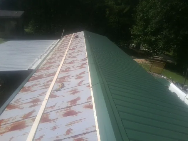 Old rusted panels beside newly installed green metal roofing — Wind Damage Roof Repair by Roofing Brothers in Washington Grove