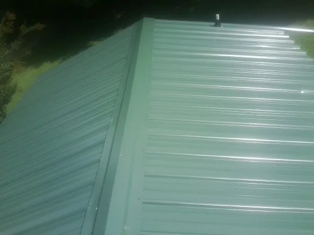 New green metal panels meeting at the ridge of a roof — Flat Roof Repair work by our crew in Washington Grove