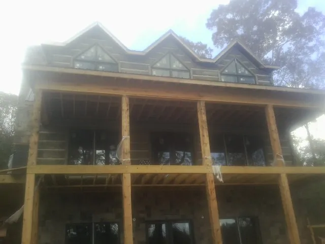 Dormers and porch framing on a large log home under construction — Roof Coating work by our crew in Washington Grove