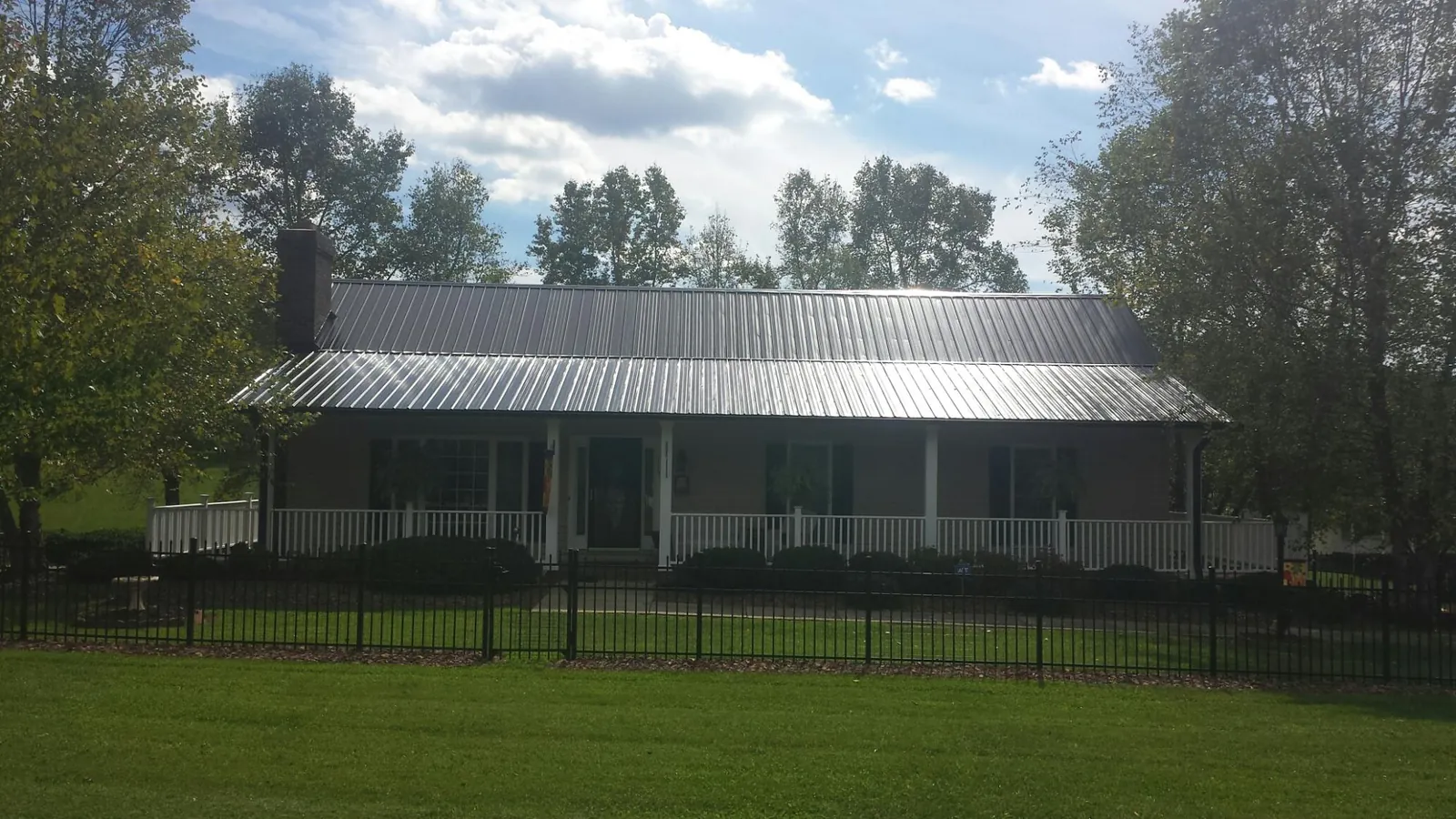 Gray metal roof on a brick ranch with a full width front porch — Gutter Guard Installation work by our crew in Washington Grove